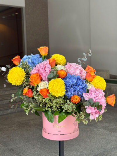 Blue and pink hydrangea box bouquet with orange roses and yellow chrysanthemums